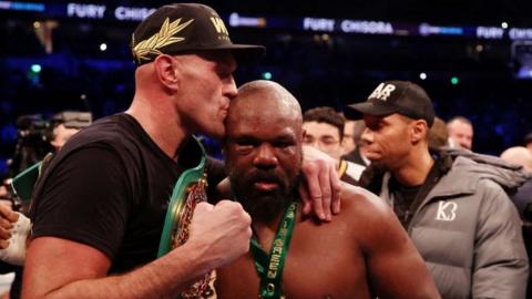 Tyson Fury kisses the head of Derek Chisora