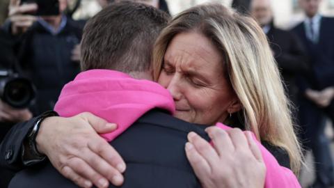 MP Kim Leadbeater with closed eyes hugging a person with their back to the camera wearing a pink hooded top