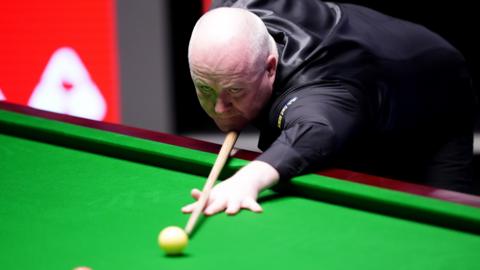 John Higgins plays a shot