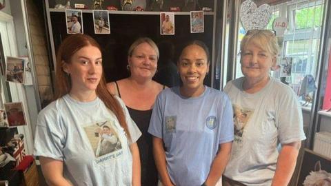 Four people standing in a line smiling, with t-shirts on which it says 'Danny's Day'