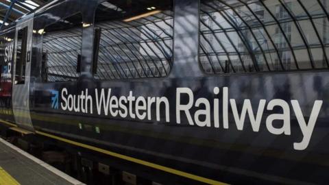 Side of dark blue train with white writing  and edge of platform