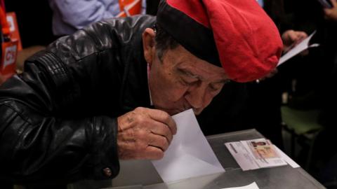 Man in traditional Catalan cap votes