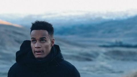 Man standing in front of snow covered hills