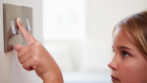 Young girl pressing light switch. 