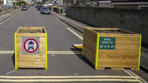 Wooden bollards preventing any motor traffic to Cowley Road as part of a low-traffic neighbourhood.