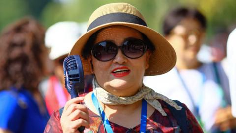  A woman cools herself with an electric portable fan