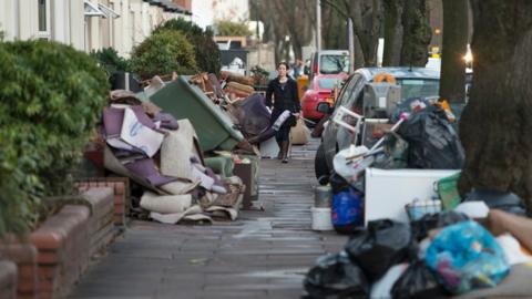 Flood damaged belongings piled up on the pavement after the River Eden burst its banks