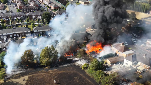 An aerial photo of a large fire at the rear of a property in a built-up residential area.
