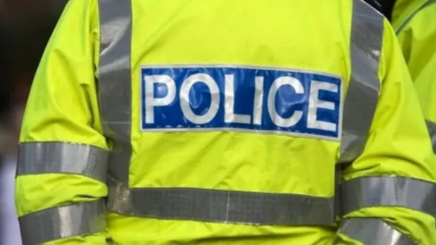 The back of a police officer wearing a high-vis jacket