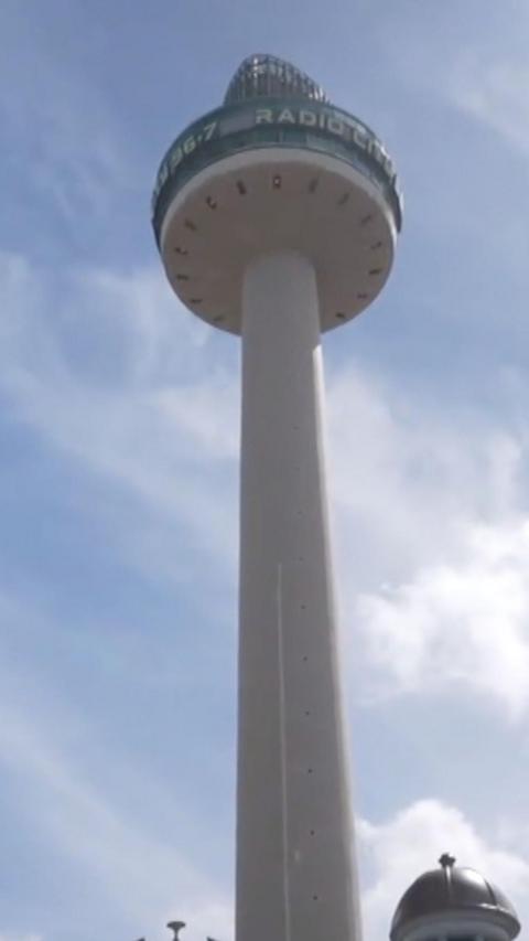 A famous landmark in Liverpool stands tall in the city with a blue sky above