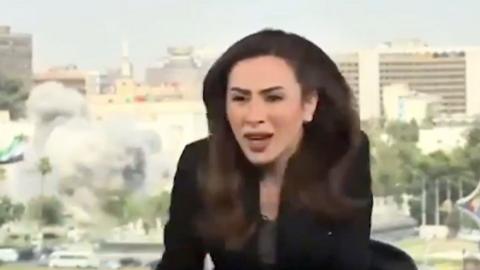 Female news presenter looks shocked as en explosion occurs behind her