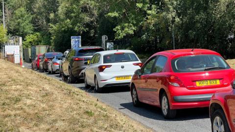 A queue of cars on a road leading into a civic tip