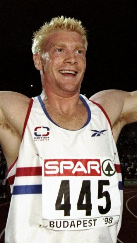 Young Iwan Thomas wears Team GB vest and is grinning as he crosses the finish line after a race
