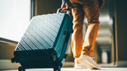A person pulls a suitcase along a corridor.