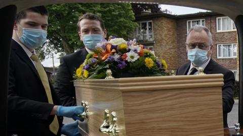 Funeral directors moving a coffin