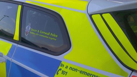 The side of a Devon & Cornwall police car painted yellow and blue and white.