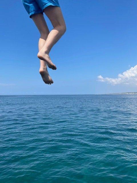 The legs of a person are seen as they dive into the sea