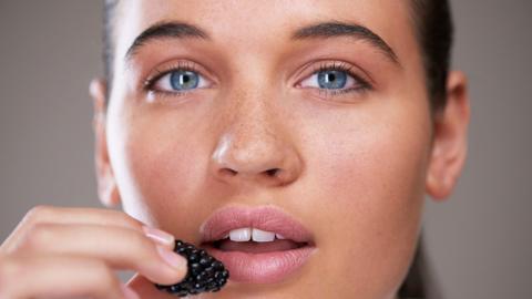 Woman eats a blackberry