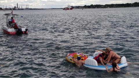 A Canadian Coast Guard ship tows floatation devices used by U.S. partiers