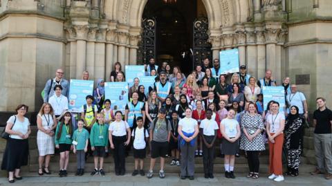 Children and some adults stood outside City Hall with posters about Clean Air Zones