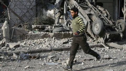 A man runs after an air raid in the besieged town of Douma, Eastern Ghouta, 23 February