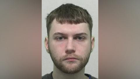 Mugshot of Tyson. He has a neat ginger beard and short dark hair.