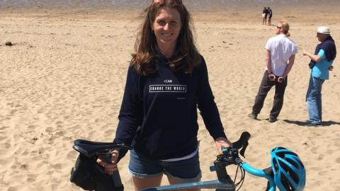 Woman with her bike on a beach