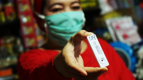 Woman holding a coronavirus test kit