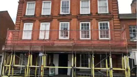 The exterior of Wilmer House, and red brick three-story building, with scaffolding around it.