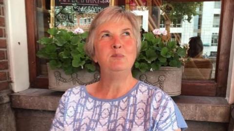 A picture of Lorraine Walker wearing a purple and white top sat outside.