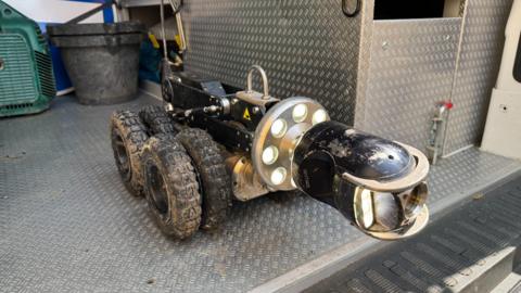 An eight wheeled robot which has a camera on the front and lights. the camera can be moved up and down. the robot goes up and down sewage pipes to inspect them.