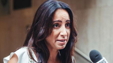 Antoinette Lattouf, wearing a white top, speaks into a microphone outside court