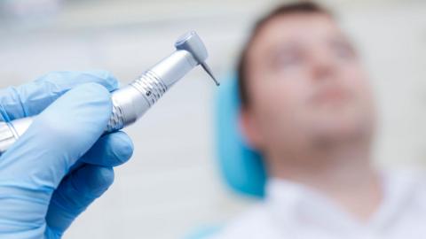 Dental patient in chair with drill in foreground 