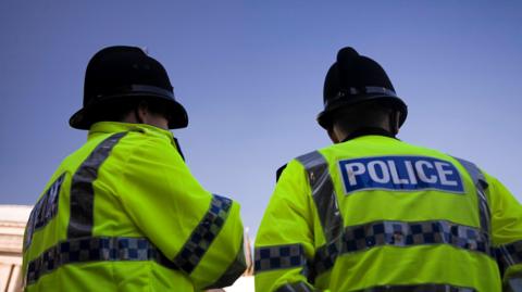 Two male police officers photographed from behind