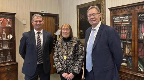 Kevin Nancekivell and Sir Gary Streeter stand either side of Lord Mayor Tina Tuohy. Both men wear navy suits. The Lord Mayor is wearing her chain. 