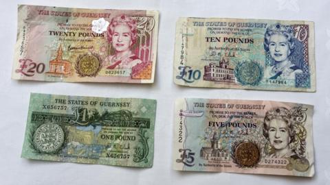 Four Guernsey bank notes lined up on a table.