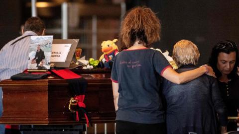 Relatives pray near the coffins of the victims of the Morandi bridge"s collapse, in Genoa, on August 17, 2018.