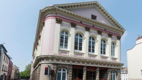 The States of Jersey (Chambre Des Etats) in St Helier in Jersey in the Channel Islands.  The building is mostly pink and white. 