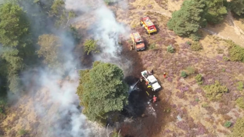 A drone image of a wildfire in Churt Common, Surrey, on 19 August. Fire engines can be seen, as well as a hose extinguishing the fire. 