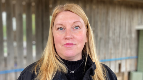 Rae Walters, who has shoulder length strawberry blonde hair, looking at the camera at the farm.