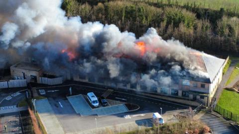 Plumes of smoke and flames pour into the sky at a school site in Devon.