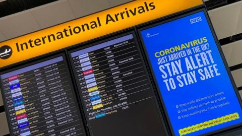 A coronavirus information notice alongside an arrivals board at London's Heathrow airport