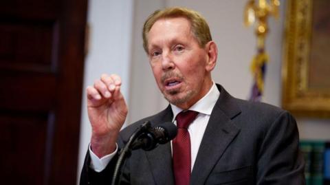 Oracle co-founder Larry Ellison gesturing while making a speech before a microphone