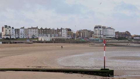 A beach with a row of buildings near it. 