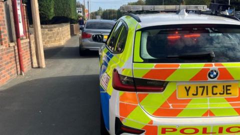 A police car stops an unisured vehicle.