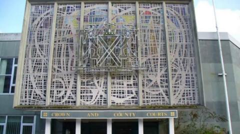 A picture of the entrance to Plymouth Crown Court. It’s a wide building with writing of the court name on the front of the building. 