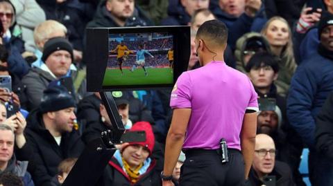 Referee Farai Hallam checks the VAR footage before deciding not to award a penalty for handball to Manchester City against Wolverhampton Wanderers