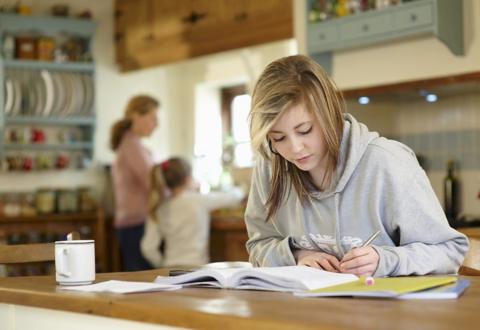 Girl sat at table doing her revision homework