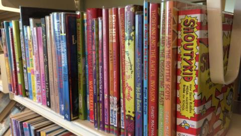 A close up photo of a bookshelf with a number of children's books on it.