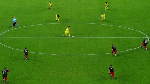 Football players kneel before kick-off